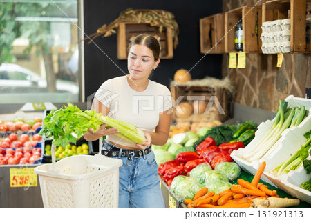 Girl customer made beeline for fresh produce section, pick bunch celery and puts it in basket. Girl customer made beeline for fresh produce section, pick bunch celery and puts it in basket. 131921313