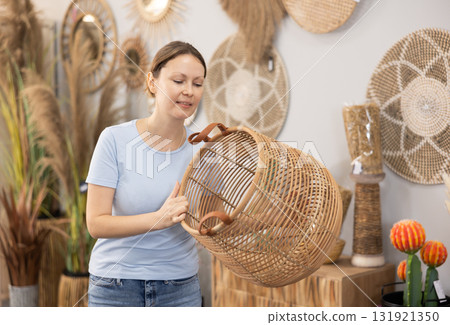Female shopper in a furniture center chooses new wicker laundry basket Female shopper in a furniture center chooses new wicker laundry basket 131921350