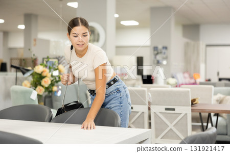 Young girl choosing functional dining table in furniture shop 131921417