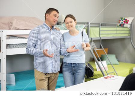 Married couple stands in childrens furniture section of store, admiring colorful and playful designs 131921419