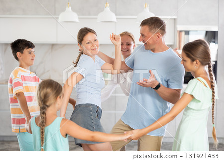 Children stand around their dancing parents in kitchen. Children stand around their dancing parents in kitchen. 131921433