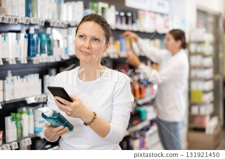 Woman shopper scanning a barcode on a cosmetics package with her phone. Searching for information via Internet 131921450