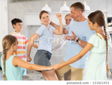 Children stand around their dancing parents in kitchen. Children stand around their dancing parents in kitchen. 131921453