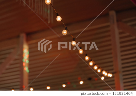Warm string lights hanging in wooden interior with blurred background Warm string lights hanging in wooden interior with blurred background 131921464