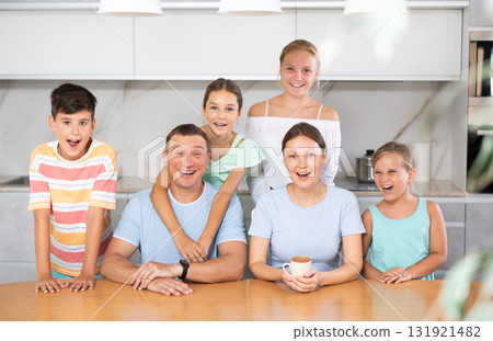 Portrait of happy family - father and mother with four children at table at home 131921482
