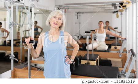 Smiling elderly woman leaning on wunda chair in pilates studio 131921519
