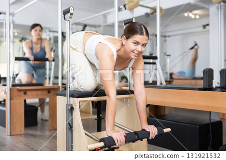Elderly woman in sportswear training pilates performer bed in gym Elderly woman in sportswear training pilates performer bed in gym 131921532