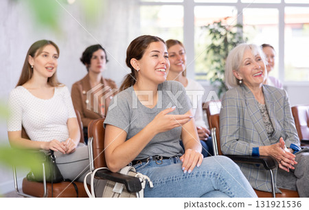 small group of women are sitting in audience, listening to lecture and laugh at amusing case small group of women are sitting in audience, listening to lecture and laugh at amusing case 131921536