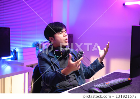 A young man enjoying playing computer games in a neon-lit room. The gaming atmosphere features vibrant colors 131921572