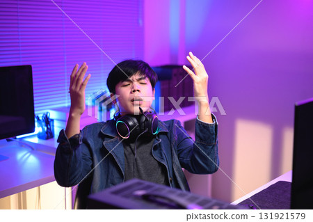A young man enjoying playing computer games in a neon-lit room. The gaming atmosphere features vibrant colors 131921579