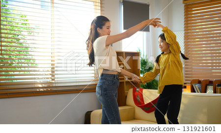 Asian mother and daughter dancing happily together in the living room 131921601