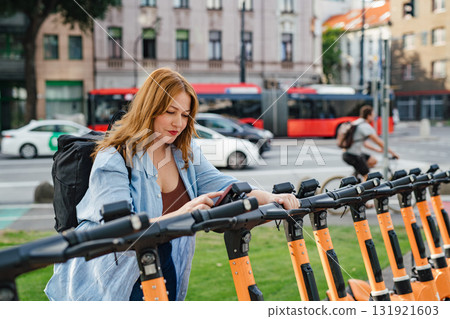 Curvy woman unlocking shared e-scooter in city. 131921603