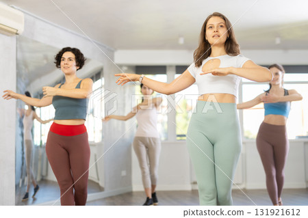 Group of active women learning modern dance movements at class together Group of active women learning modern dance movements at class together 131921612