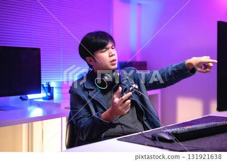 A young man enjoying playing computer games in a neon-lit room. The gaming atmosphere features vibrant colors A young man enjoying playing computer games in a neon-lit room. The gaming atmosphere features vibrant colors 131921638