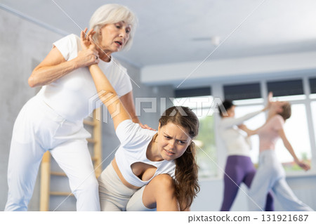 Mature woman applying arm lock technique in mock bout during self-defense class Mature woman applying arm lock technique in mock bout during self-defense class 131921687
