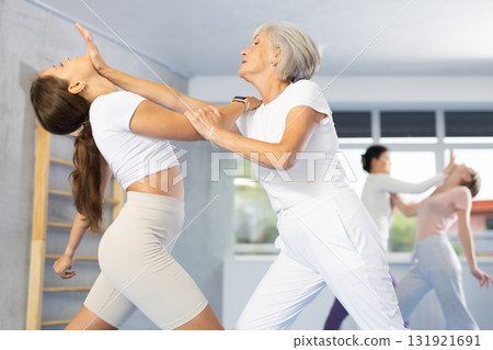 Senior woman using palm to launch blow in chin in sparring during self-defense training 131921691