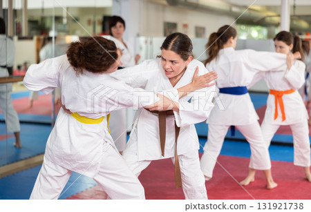 Womens working in pair mastering new karate moves during group class 131921738