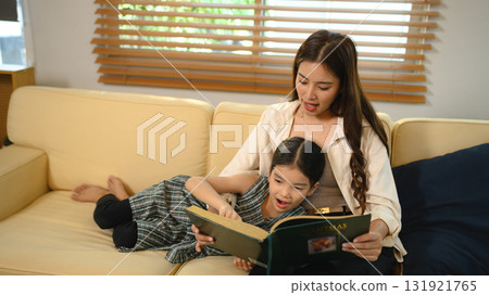 Happy mom and little girl bonding while reading storybook at home 131921765