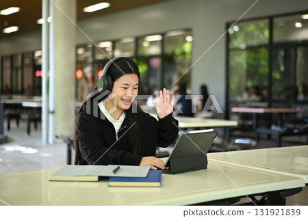 Cheerful high school girl attending online course in modern school environment 131921839