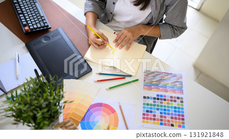 Creative artist developing branding ideas by hand drawing logo designs and selecting color palettes 131921848