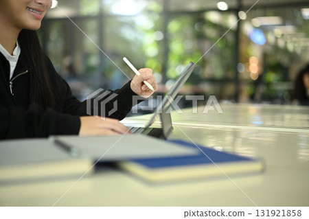 Close-up view of young female student working on digital tablet for homework or virtual class 131921858
