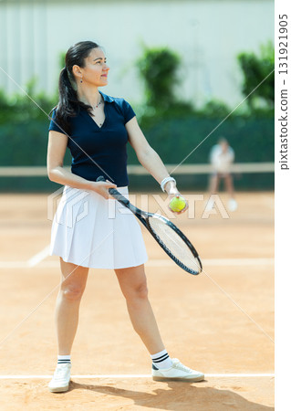 Adult woman plays tennis on tennis court 131921905