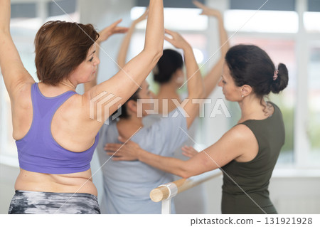 Adult woman teacher correcting beginning dancers Adult woman teacher correcting beginning dancers 131921928