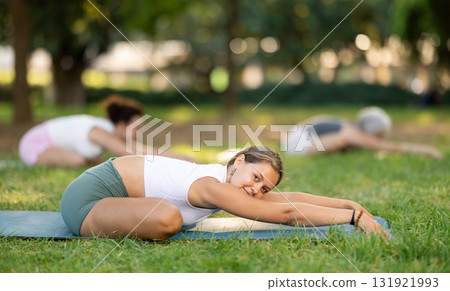 Young female yoga instructor leading outdoor group class 131921993