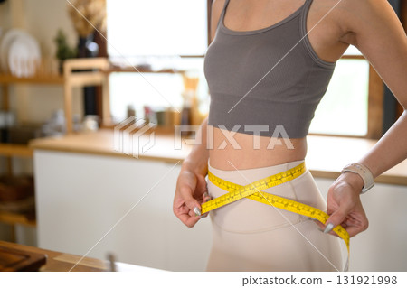 Female measuring waistline to track progress for weight loss, diet, or body shaping program 131921998