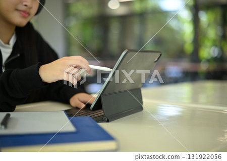Cropped shot teenage student studying with tablet at school table, showing commitment and concentration Cropped shot teenage student studying with tablet at school table, showing commitment and concentration 131922056