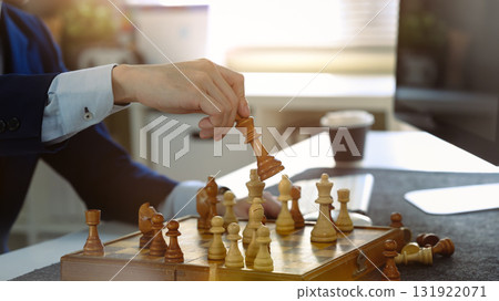 Businessman making checkmate move in chess game, symbolizing strategic decision and successful business planning 131922071
