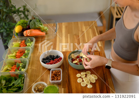 Female hands arranging fruits into a yogurt bowl, healthy breakfast concept with clean eating and wellness. Female hands arranging fruits into a yogurt bowl, healthy breakfast concept with clean eating and wellness. 131922091