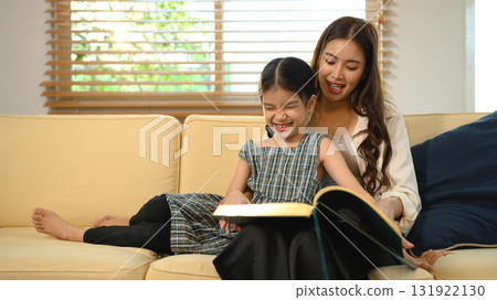 A loving mother spends quality time reading with her daughter at home, creating warm memories and encouraging learning 131922130