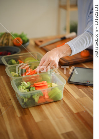 Closeup attractive woman arranging her dividing food into meals Closeup attractive woman arranging her dividing food into meals 131922131