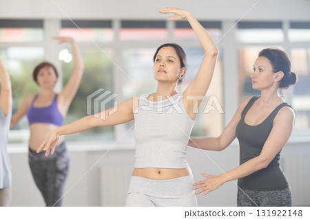 Asian woman enjoying ballet practice with instructor in group class Asian woman enjoying ballet practice with instructor in group class 131922148