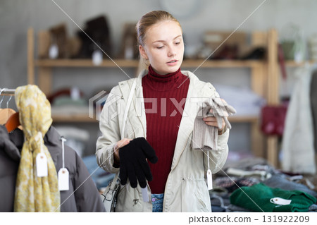 Teenage girl choosing winter gloves in clothing store 131922209