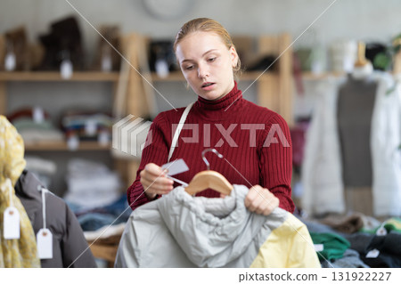 Attentive teenage girl choosing lightweight jacket in clothing store Attentive teenage girl choosing lightweight jacket in clothing store 131922227