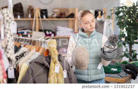Teenage girl choosing hat in clothing store Teenage girl choosing hat in clothing store 131922237