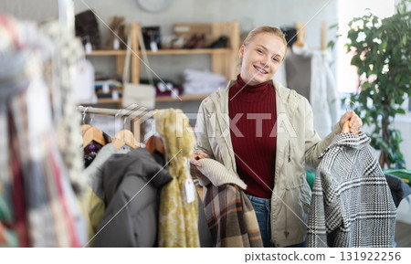 While shopping, teen girl browsing goods items and choose elect checkered coat in store While shopping, teen girl browsing goods items and choose elect checkered coat in store 131922256