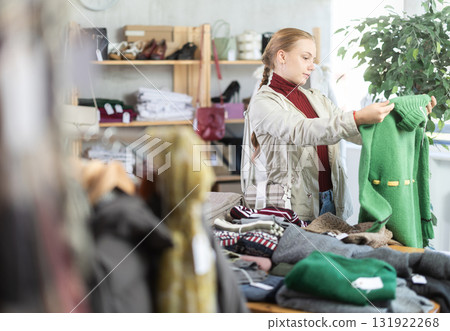 Selective teen girl choosing sweater in clothing store Selective teen girl choosing sweater in clothing store 131922268