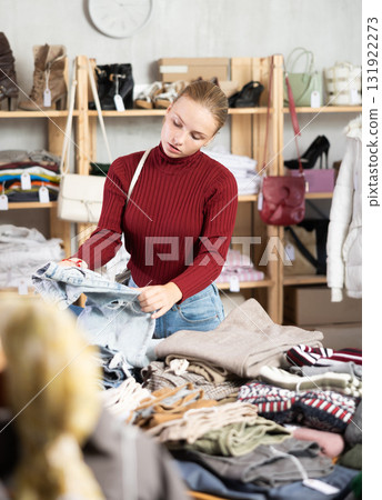 While shopping, teen girl browsing goods items and choose elect denim trousers in store 131922273
