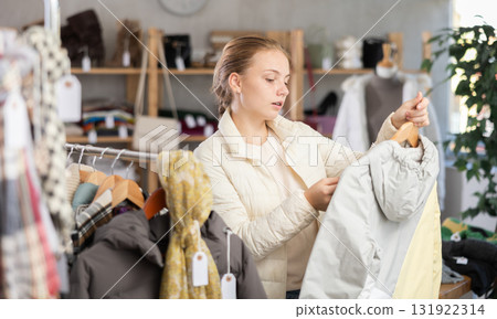 Attentive teenage girl choosing lightweight jacket in clothing store 131922314