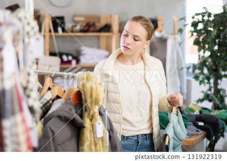 While shopping, teen girl browsing goods items and choose elect something warm outerwear in store 131922319