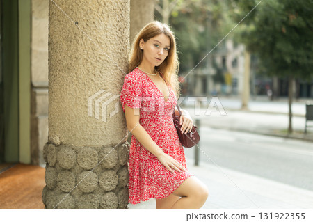 Young woman standing near a column on the street 131922355
