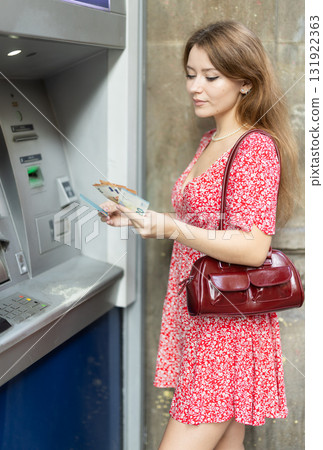 Young woman withdrawing a day from an atm Young woman withdrawing a day from an atm 131922363