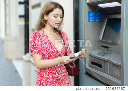 Young woman withdrawing a day from an atm Young woman withdrawing a day from an atm 131922367