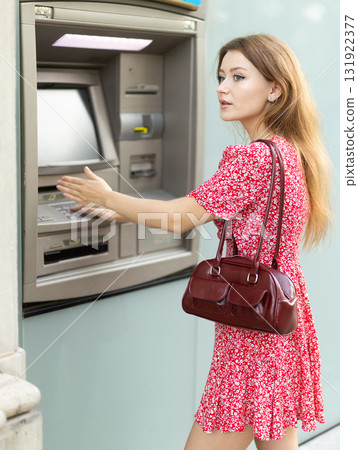 Young woman carefully entering pin code at atm 131922377
