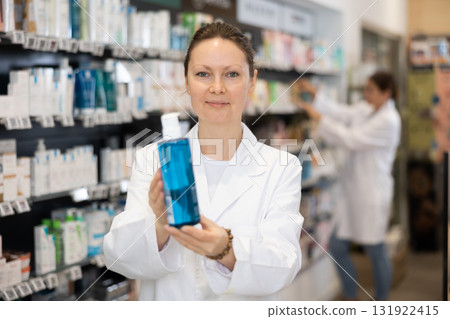 Female pharmacist offers cosmetics products while standing in the trading floor of pharmacy Female pharmacist offers cosmetics products while standing in the trading floor of pharmacy 131922415
