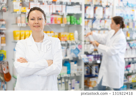 At pharmacy, apothecary waiting for customers and invites with gesture go to department of cosmetics At pharmacy, apothecary waiting for customers and invites with gesture go to department of cosmetics 131922418
