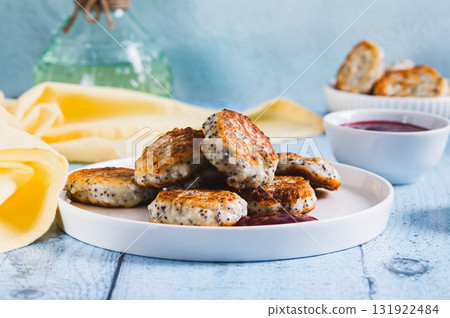 Mini cottage cheese pancakes with poppy seeds and berry jam on a plate on the table 131922484